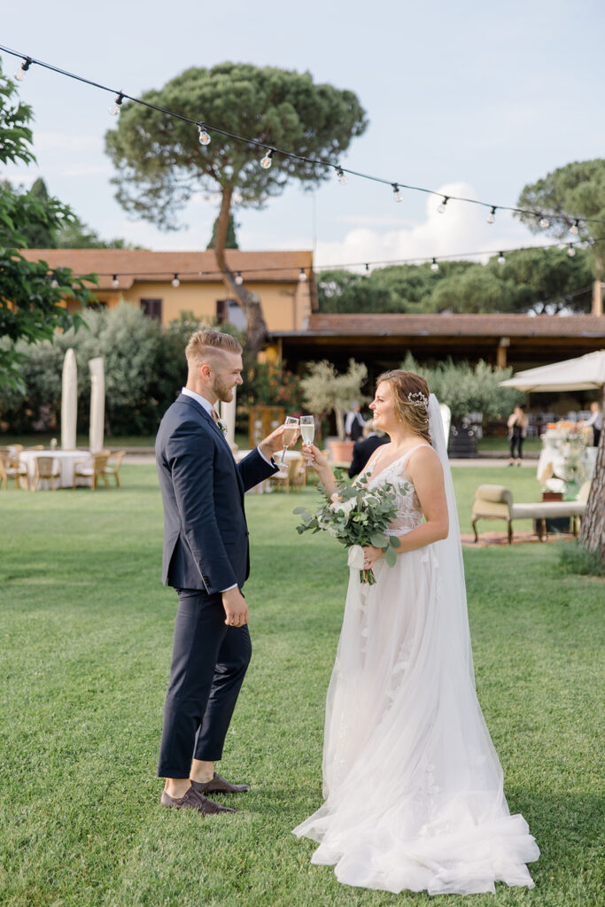 bride and groom have their first cheers as newlyweds in front of reception space at Rome countryside wedding held at Tenuta La Porta Sul Lago photographed by Destination Wedding Photographer Brittany Navin Photography