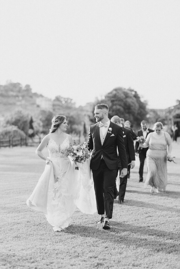 bride and groom walking with guests following at Rome countryside wedding held at Tenuta La Porta Sul Lago photographed by Destination Wedding Photographer Brittany Navin Photography