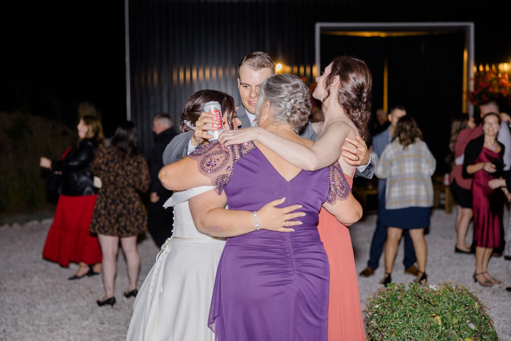 group hug on the outdoor dance floor at Bleeks and Bergamot wedding in Ashton, Ontario photographed by Ottawa wedding photographer, Brittany Navin Photography