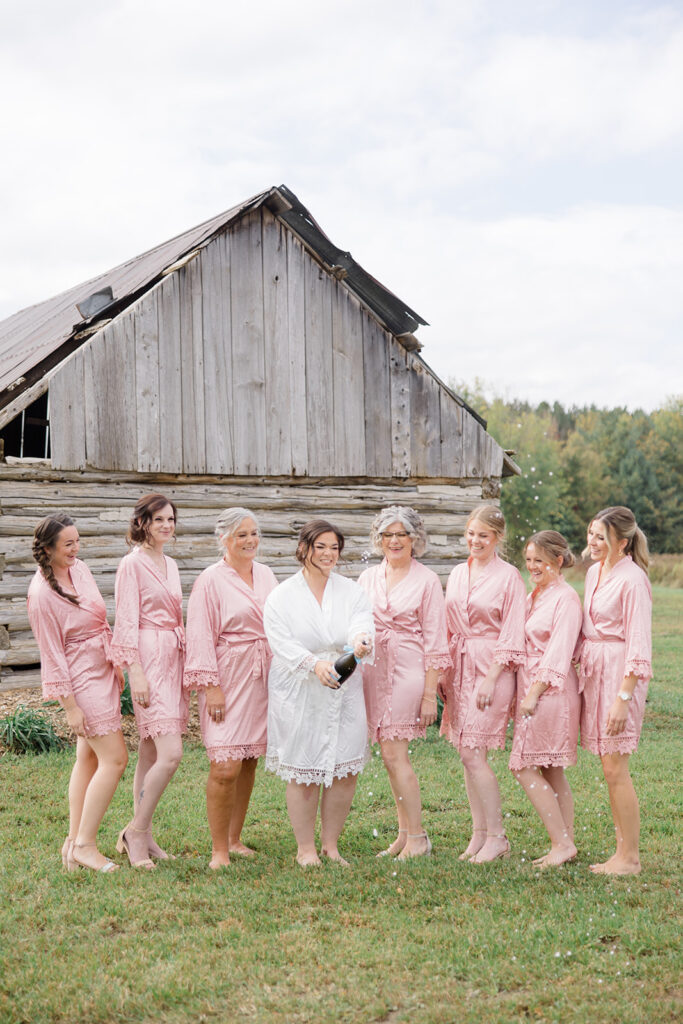 bride and her ladies popping champagne in their matching robes at Bleeks and Bergamot wedding in Ashton, Ontario photographed by Ottawa wedding photographer, Brittany Navin Photography