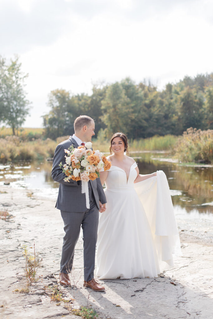 bride and groom walking along the river rock at Bleeks and Bergamot wedding in Ashton, Ontario photographed by Ottawa wedding photographer, Brittany Navin Photography