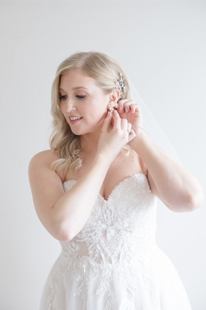 bride putting in her earrings the morning of the wedding photographed by Brittany Navin Photography