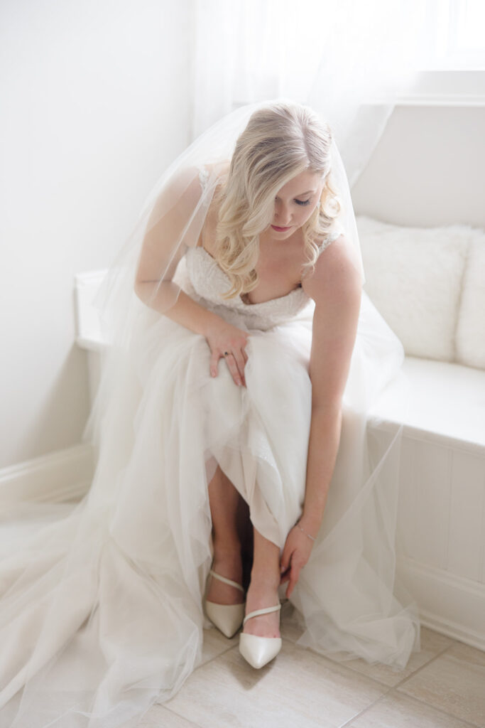 Bride doing up her shoes in the bridal suite at Stonefields Estate wedding photographed by Ottawa Wedding Photographer Brittany Navin Photography