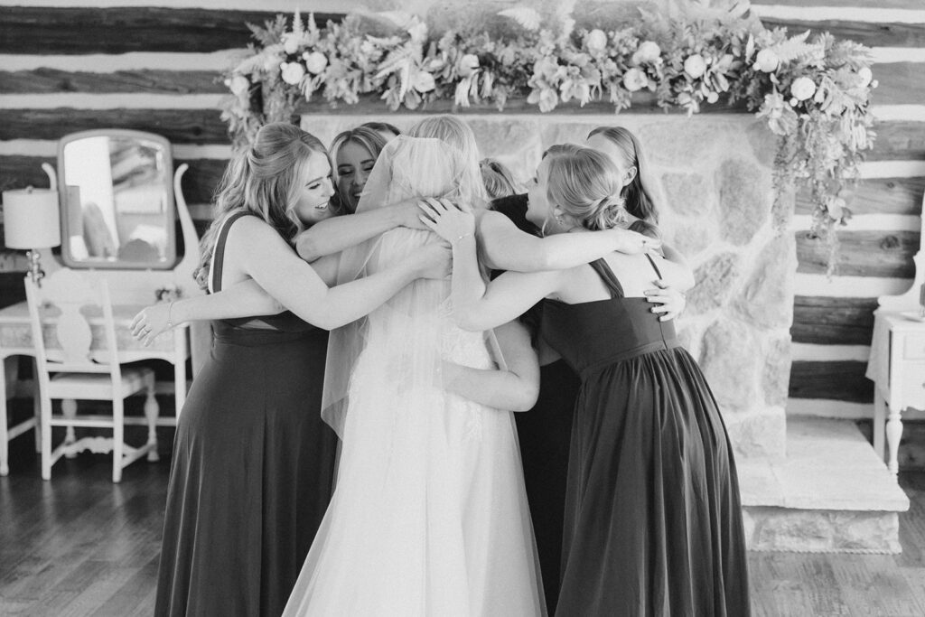bride and bridesmaids go in for a big group hug after seeing each other all ready at Stonefields Estate wedding photographed by Ottawa Wedding Photographer Brittany Navin Photography