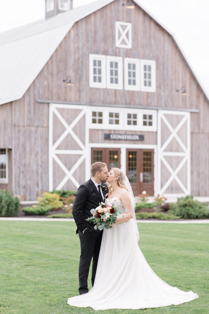 bride and groom share a first kiss in front of the loft at Stonefields Estate wedding photographed by Ottawa Wedding Photographer Brittany Navin Photography