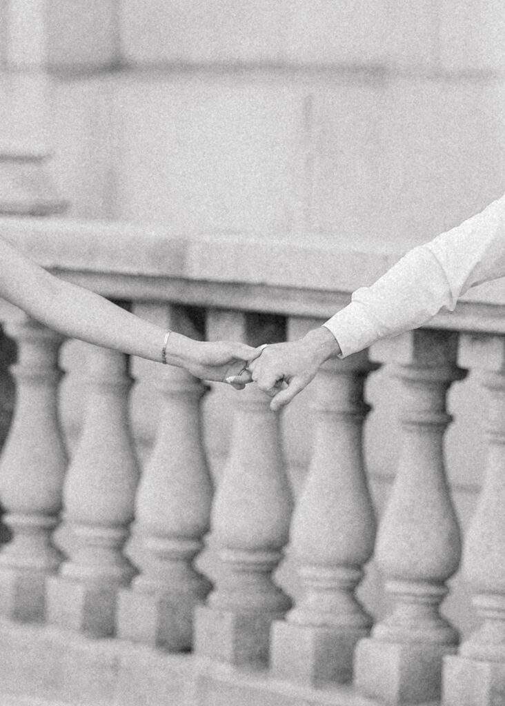 Couple holding hands at Château Laurier engagement photos, wearing modern, classic white and black outfits.