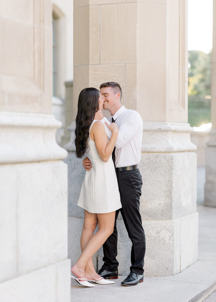 Couple smiling at each other during their Château Laurier engagement photos, wearing modern, classic white and black outfits.
