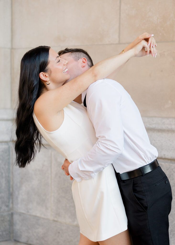 Couple hugging during their Château Laurier engagement photos, wearing modern, classic white and black outfits.