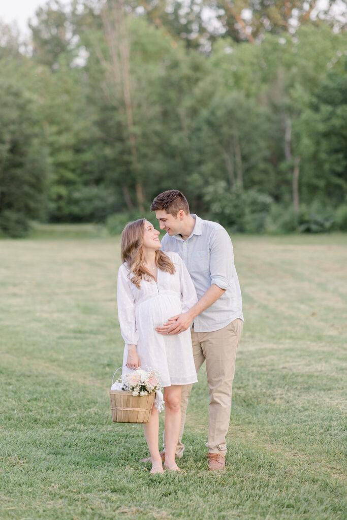 couple holding baby bump and basket of florals at dominion arboretum maternity session in Ottawa photographed by Brittany Navin