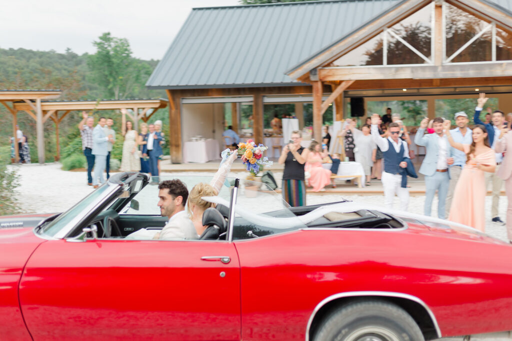 bride and groom draving by as their guests cheer them on at Le Peaches and Cream Wedding photographed by Ottawa wedding photographer, Brittany Navin