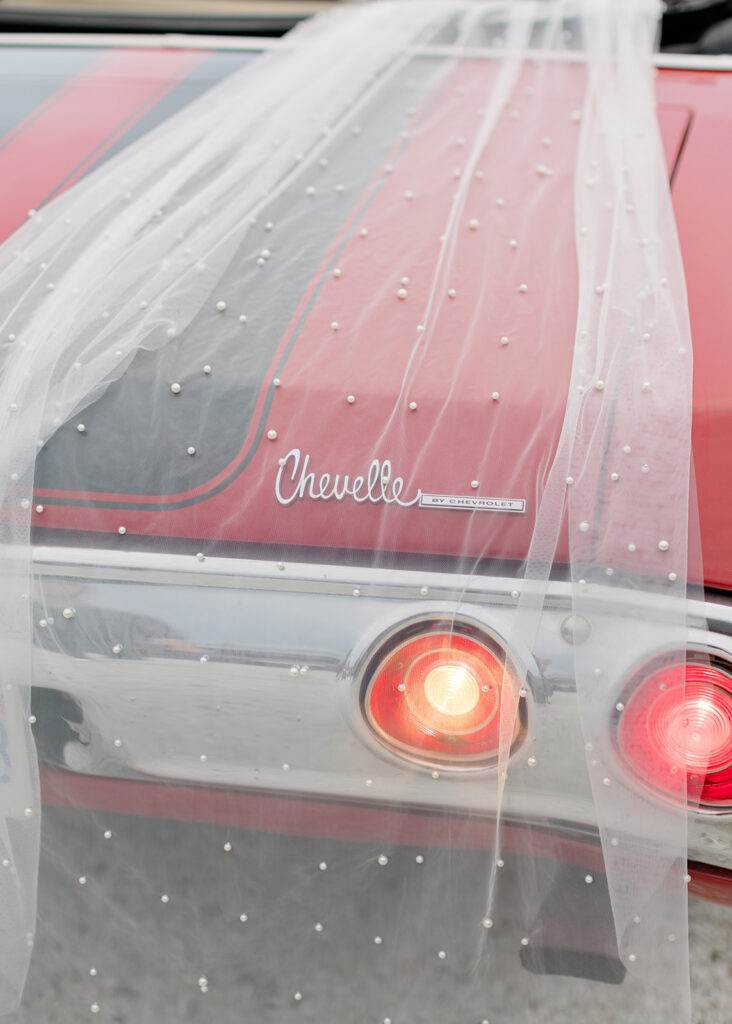 brides veil with pearl beads draped over the back of the Chevelle 